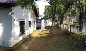 Imagem 6: Casarão antigo de esquina, com amplo jardim e gramado em volta da casa, com árvores frutíf