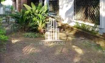 Imagem 4: Casarão antigo de esquina, com amplo jardim e gramado em volta da casa, com árvores frutíf