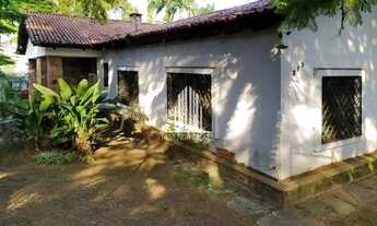 Imagem 2: Casarão antigo de esquina, com amplo jardim e gramado em volta da casa, com árvores frutíf