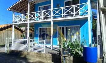 Imagem 2: Casa charmosa em estilo praiano, com fachada colorida e ampla varanda que integra os ambie