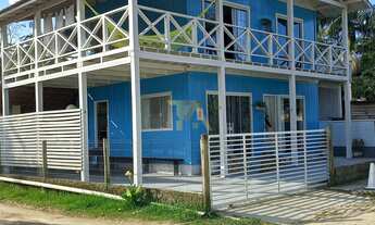 Imagem 3: Casa charmosa em estilo praiano, com fachada colorida e ampla varanda que integra os ambie