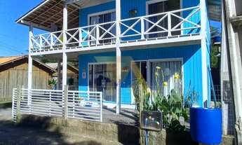 Imagem 2: Casa charmosa em estilo praiano, com fachada colorida e ampla varanda que integra os ambie