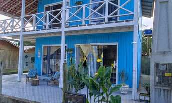 Imagem 4: Casa charmosa em estilo praiano, com fachada colorida e ampla varanda que integra os ambie